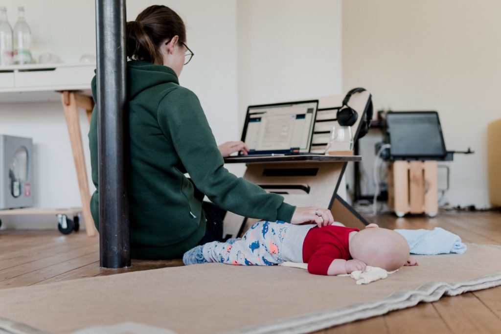 Mãe trabalhando no computador e cuidando do filho ao mesmo tempo - paralelização de tarefas