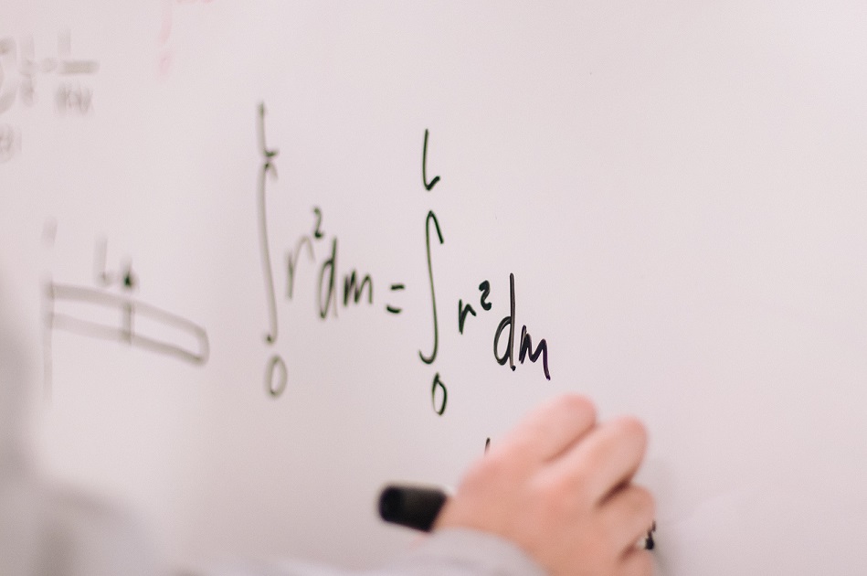 Pessoa escrevendo equações matemáticas em quadro branco